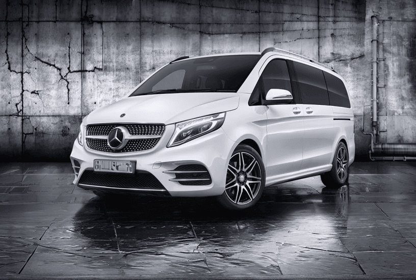 White Mercedes-Benz van parked in front of a grungy, cracked concrete wall.