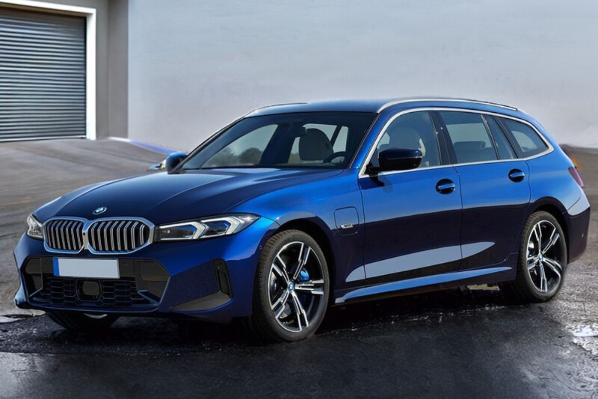 A blue station wagon car parked outdoors in front of a garage.